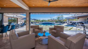 Un espace intérieur moderne avec vue sur la piscine, des sièges en cuir et un ventilateur de plafond.