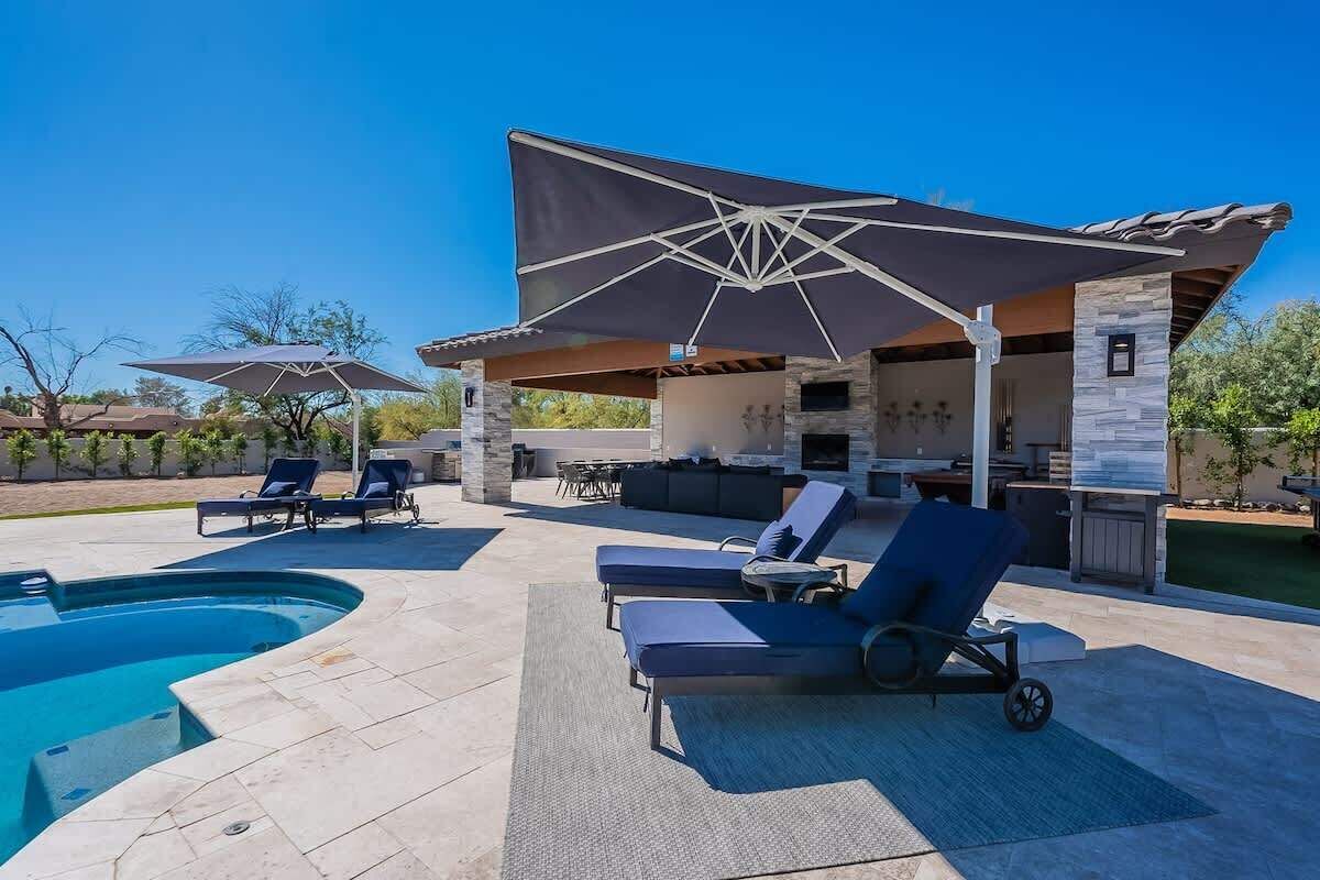Un espace aménagé au bord de la piscine, avec des chaises longues, un coin salon abrité et un barbecue.