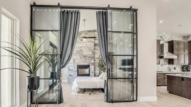 Un intérieur moderne avec une porte-fenêtre coulissante donnant sur une chambre, une cheminée et un coin cuisine.