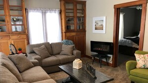 A living room with a sectional sofa, a coffee table, a fireplace, and a television.