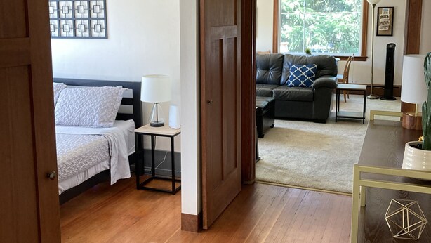 A room with a bed, a desk, a sofa, and a window.