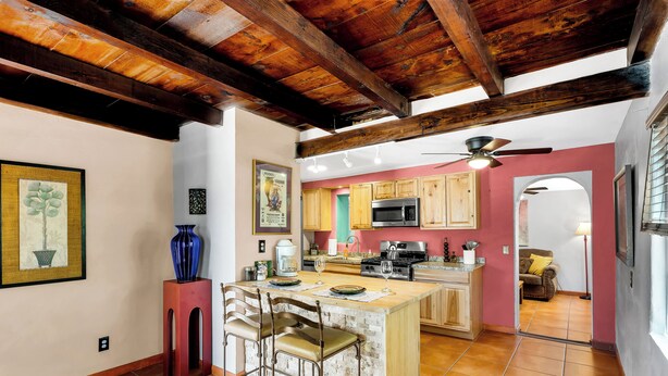 A kitchen with a central island, wooden beams, a ceiling fan, and a view into another room. - “La Casita Encantada” All the Charm & all the Amenties for a Long or Short Stay! (Tucson)