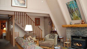 Ein Loft-Wohnzimmer mit hohen Decken, Kamin, Treppe und einem großen Gemälde.