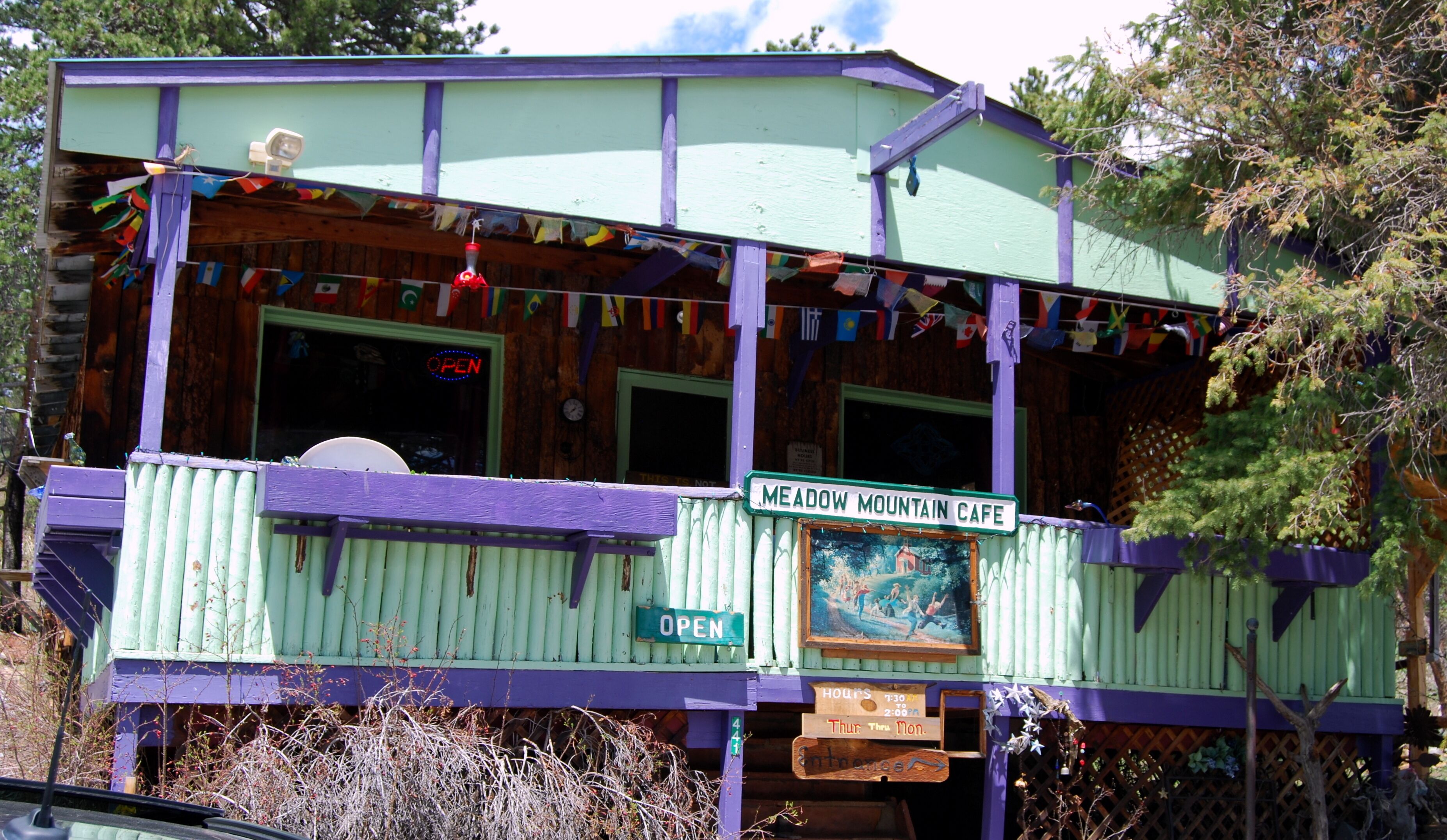A two-story building with a sign reading 'MEADOW MOUNTAIN CAFE' and an 'OPEN' sign.
