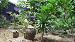 A garden with a large planter, a wooden bench, and a hose. - Sichang My Home (Ko Sichang)