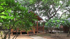 A wooden structure with a covered porch and a concrete pathway leading to it. - Sichang My Home (Ko Sichang)