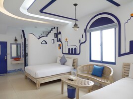 A bedroom with a bed, a wooden bench, a small table, and a window.