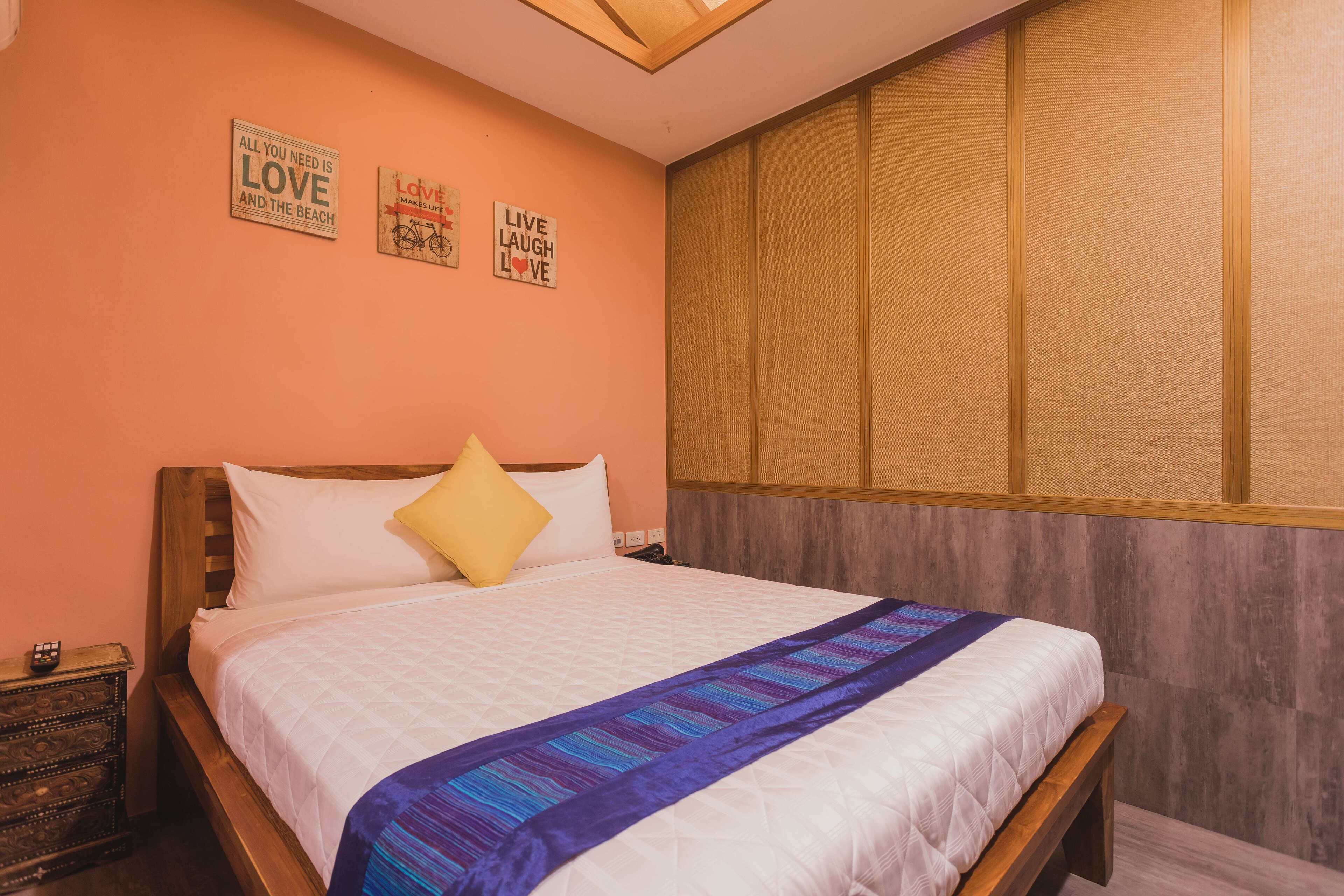 A neatly made bed with a white and blue striped blanket, a wooden headboard, and a nightstand with a small lamp.