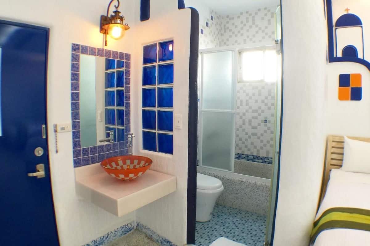 Un baño con lavamanos blanco, espejo y zona de ducha.
