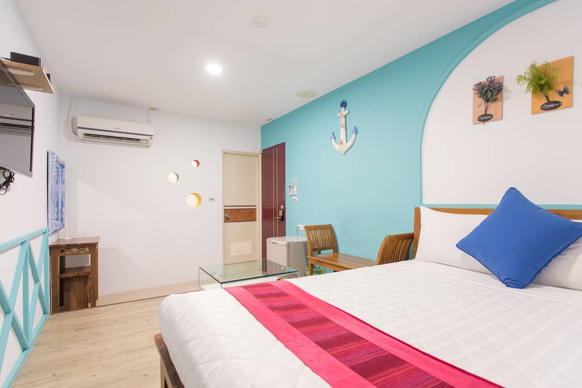 Habitación de hotel con una cama, un escritorio, una silla y una mesita.