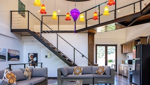 Uma sala de estar ampla com uma escada moderna, uma cozinha e um espaço de jantar.