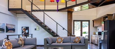 Amplia sala de estar con una escalera moderna, una cocina y un comedor.