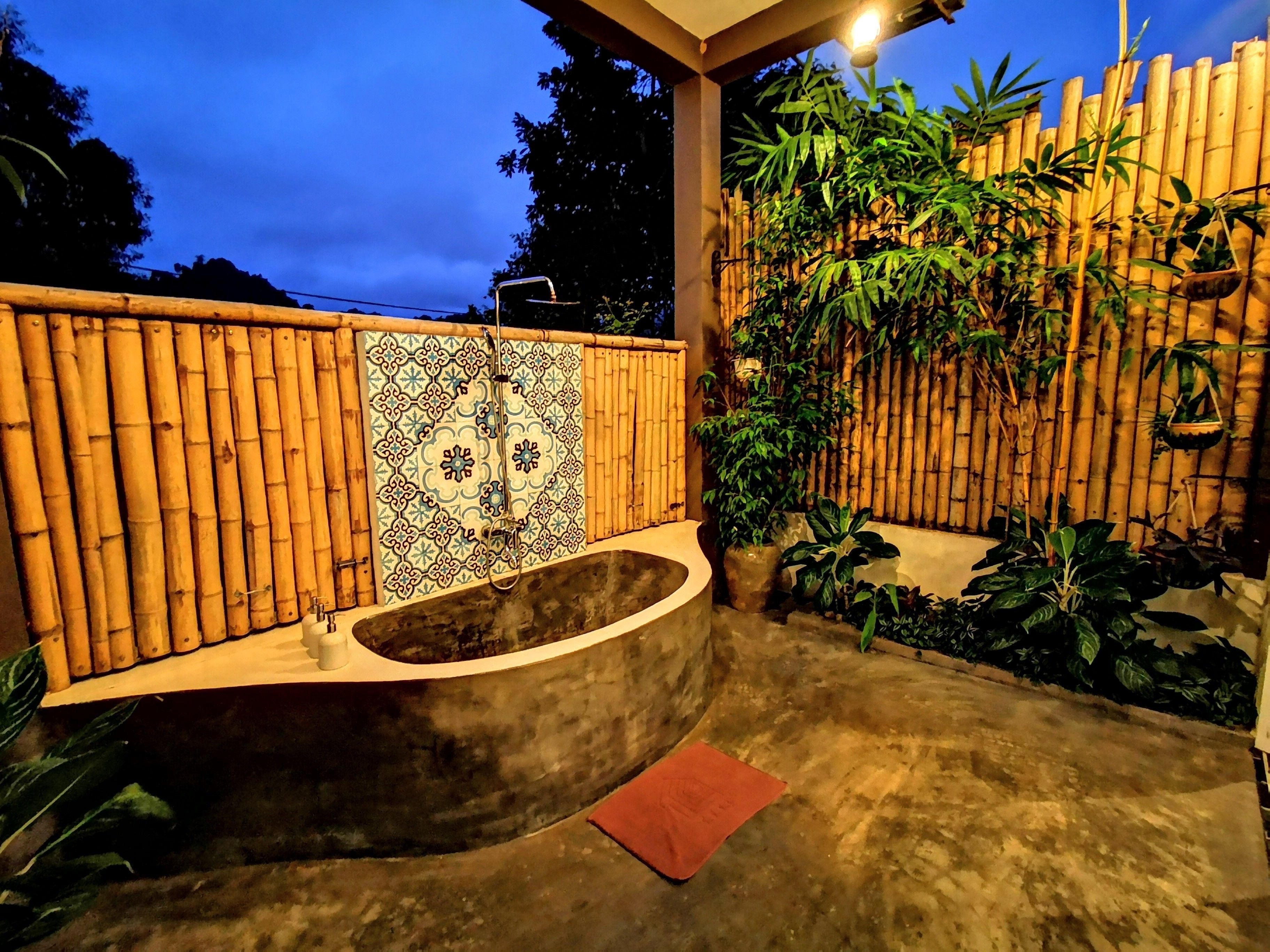 A spa area with a freestanding bathtub, bamboo wall, and tiled floor.