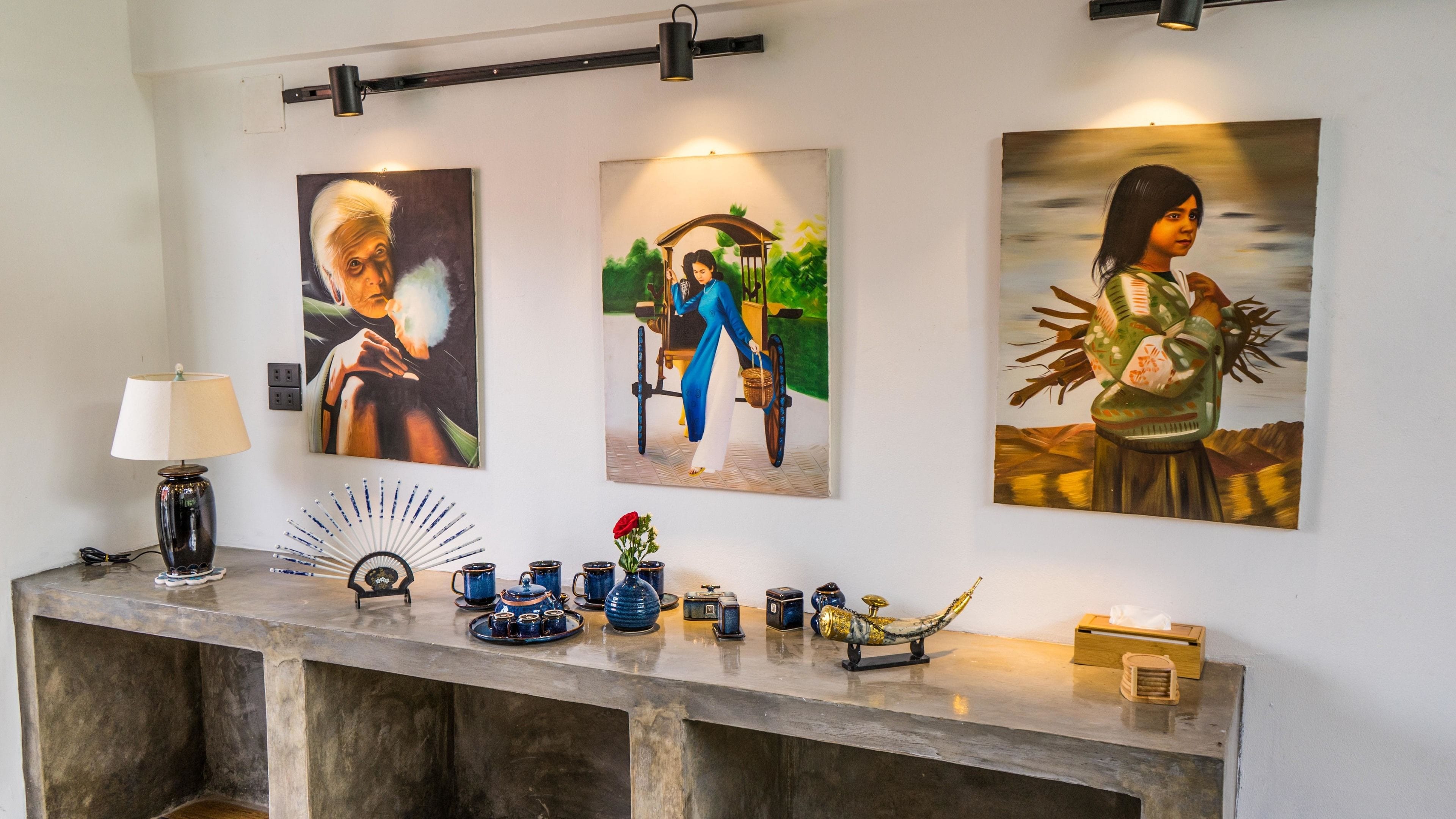 A room with a marble reception desk, a lamp, and three framed paintings on the wall.