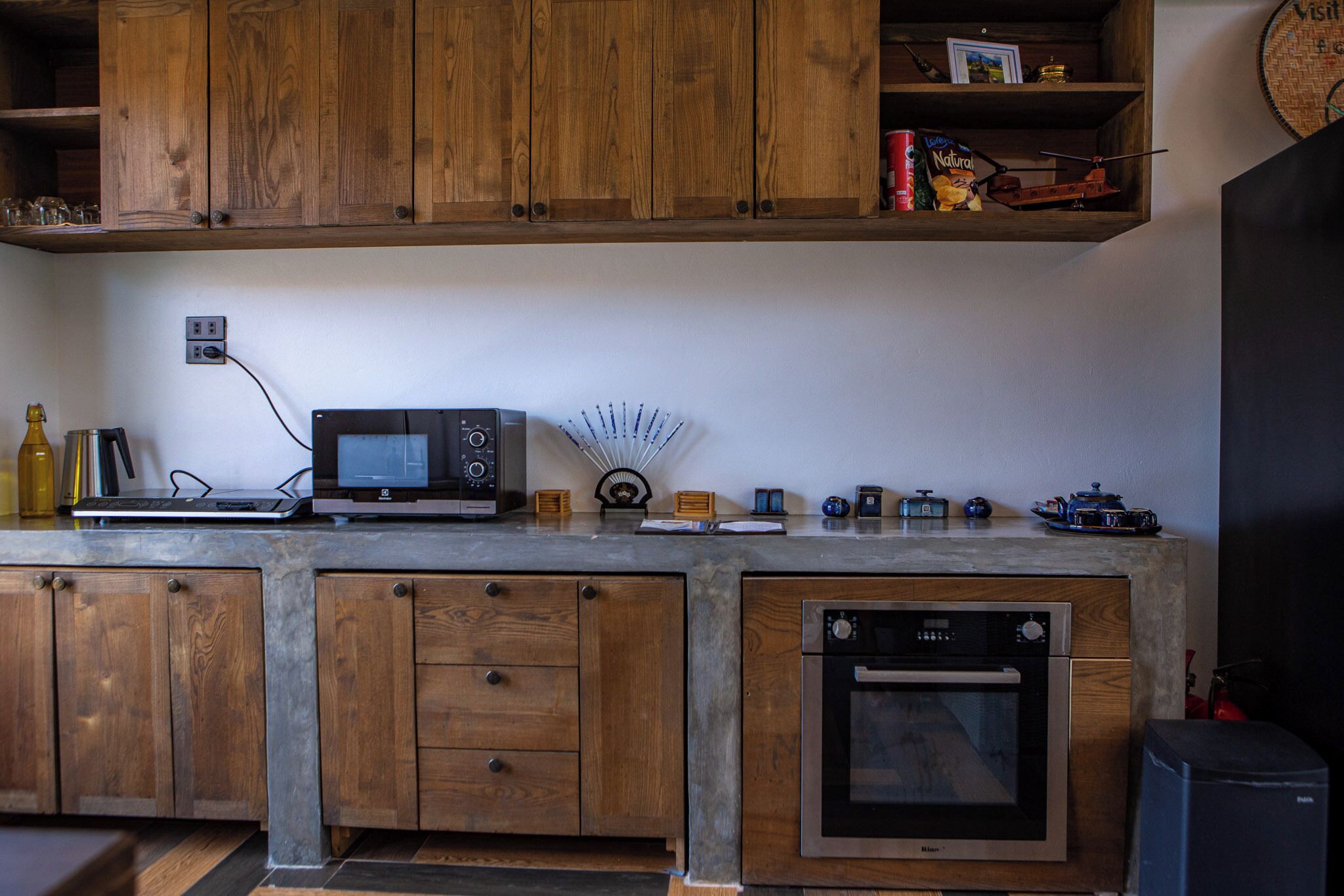A kitchen with wooden cabinets, a microwave, a coffee maker, and a small oven.