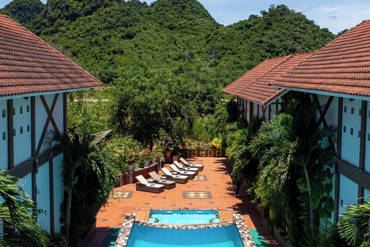 A pool area with lounge chairs and a view of lush green hills.