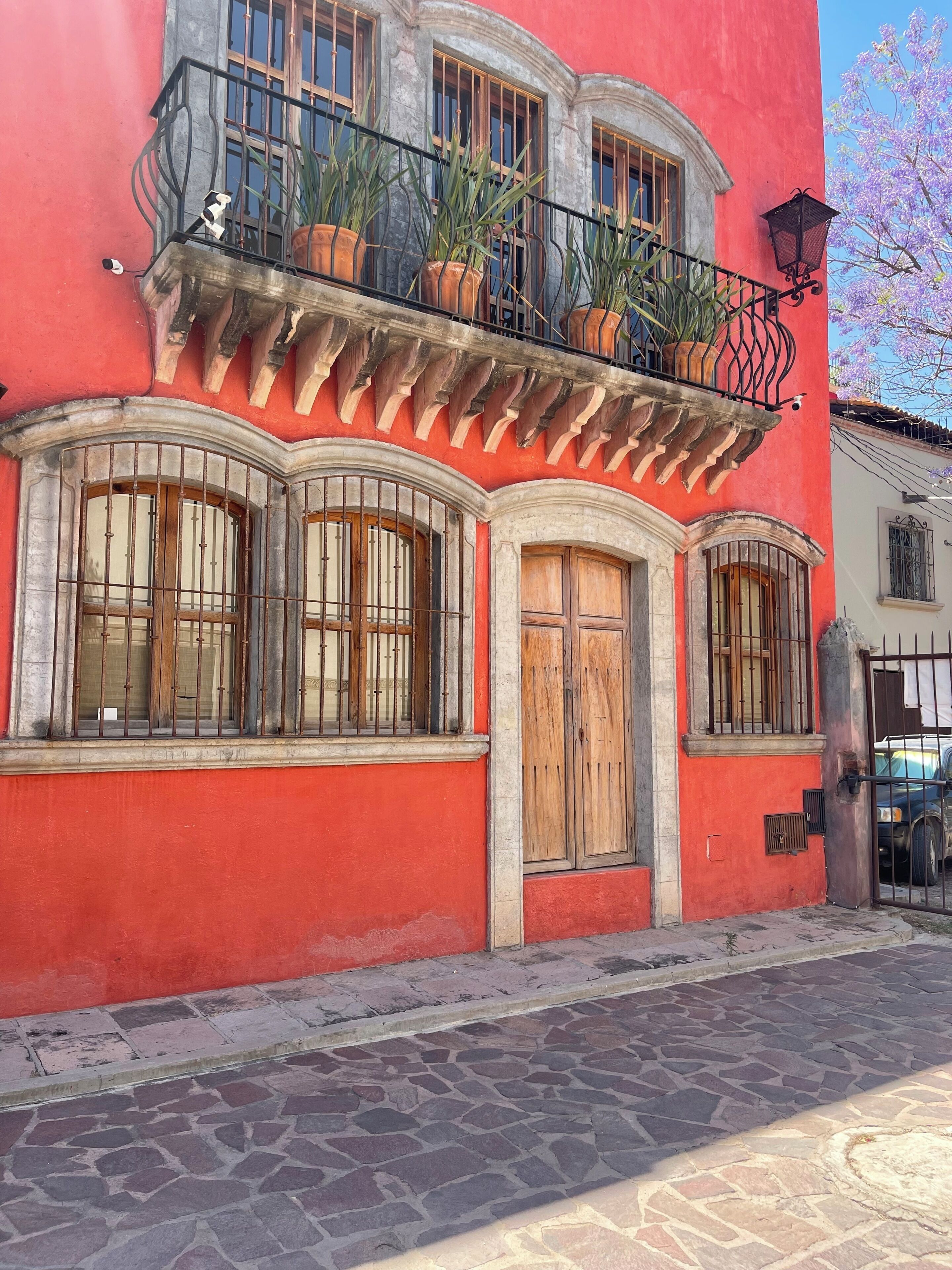 Un edificio rojo con balcón, ventanas grandes y puerta de madera.