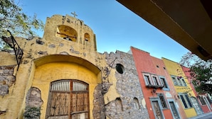 Um edifício histórico com uma grande porta de madeira, paredes de pedra e um campanário.