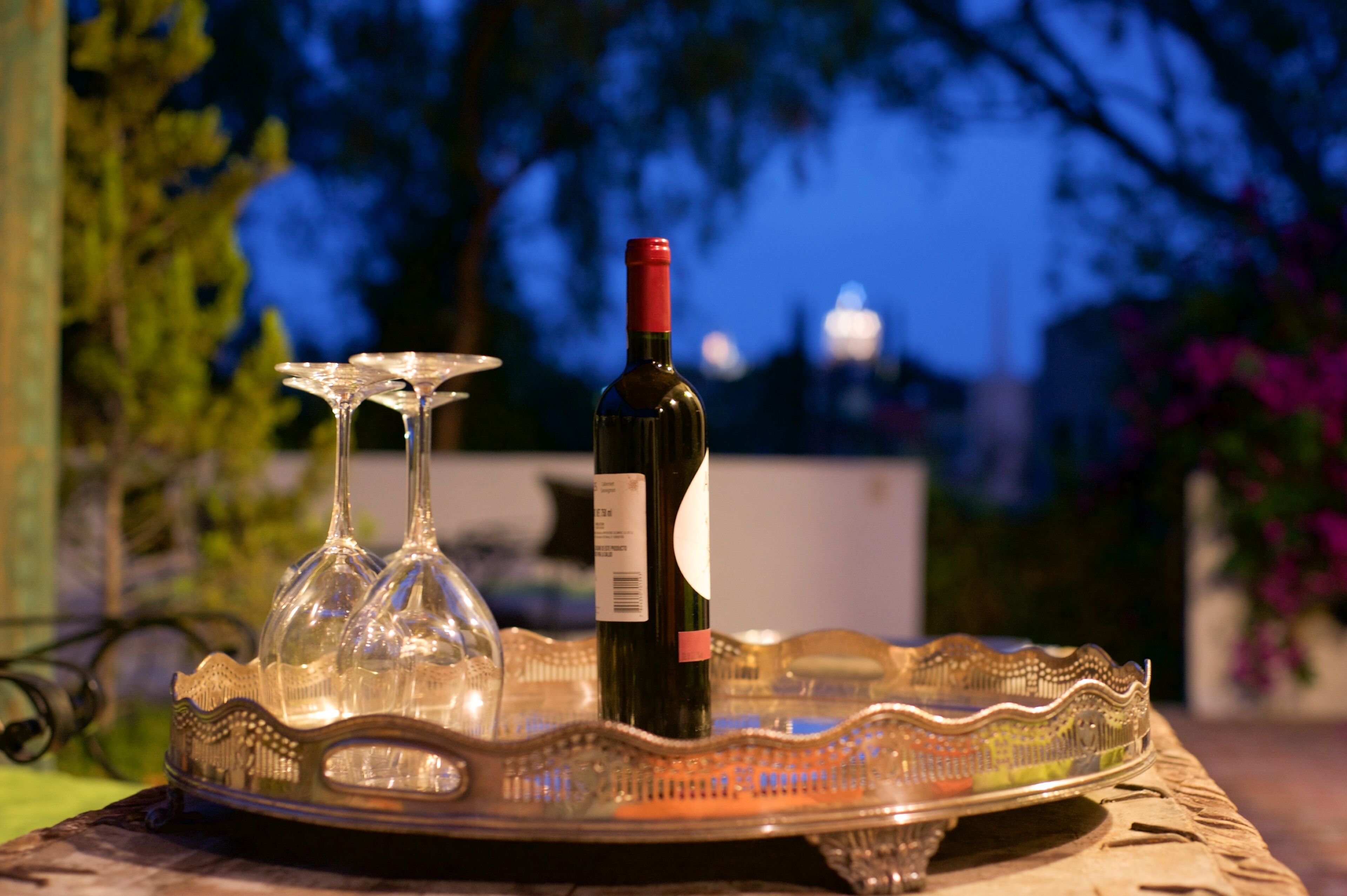 A bottle of wine on a tray with two wine glasses.