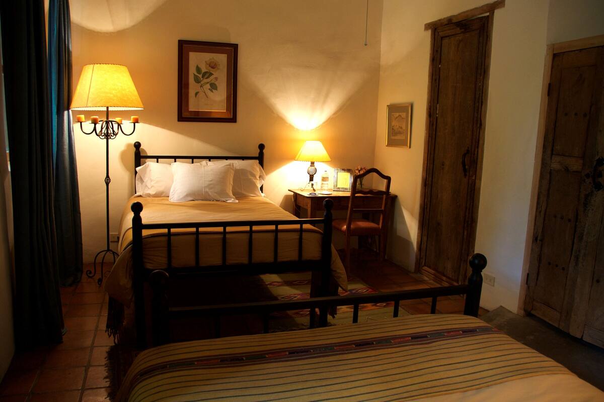 Ein Schlafzimmer mit Bett, Nachttisch, Lampe, Sessel und Kleiderschrank.