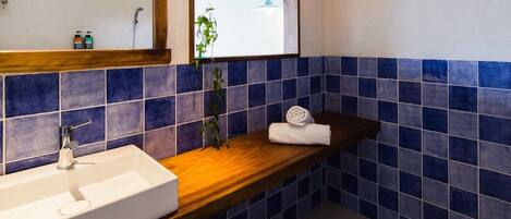 A bathroom with a white sink, a wooden countertop, a mirror, and blue-tiled walls.