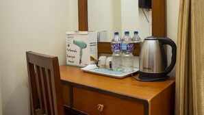 Ein Holztisch mit einem Spiegel, einer Box mit dem Aufdruck 'Kathmandu Boutique Hotel', zwei Wasserflaschen, einer Kaffeemaschine und einer Tasse.