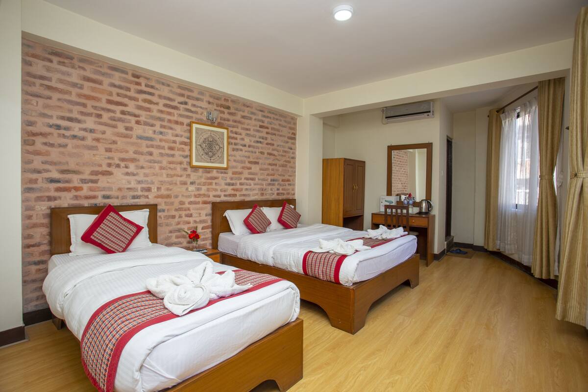 Una habitación de hotel con dos camas de madera, una pared de ladrillo y suelo de madera.