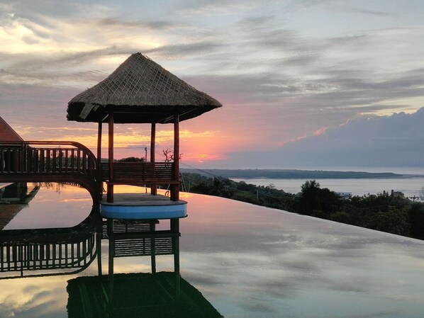 A gazebo with a thatched roof overlooking a body of water, with a clear view of the horizon. - Semabu Hills Hotel Nusa Penida - Bali (Penida Island)