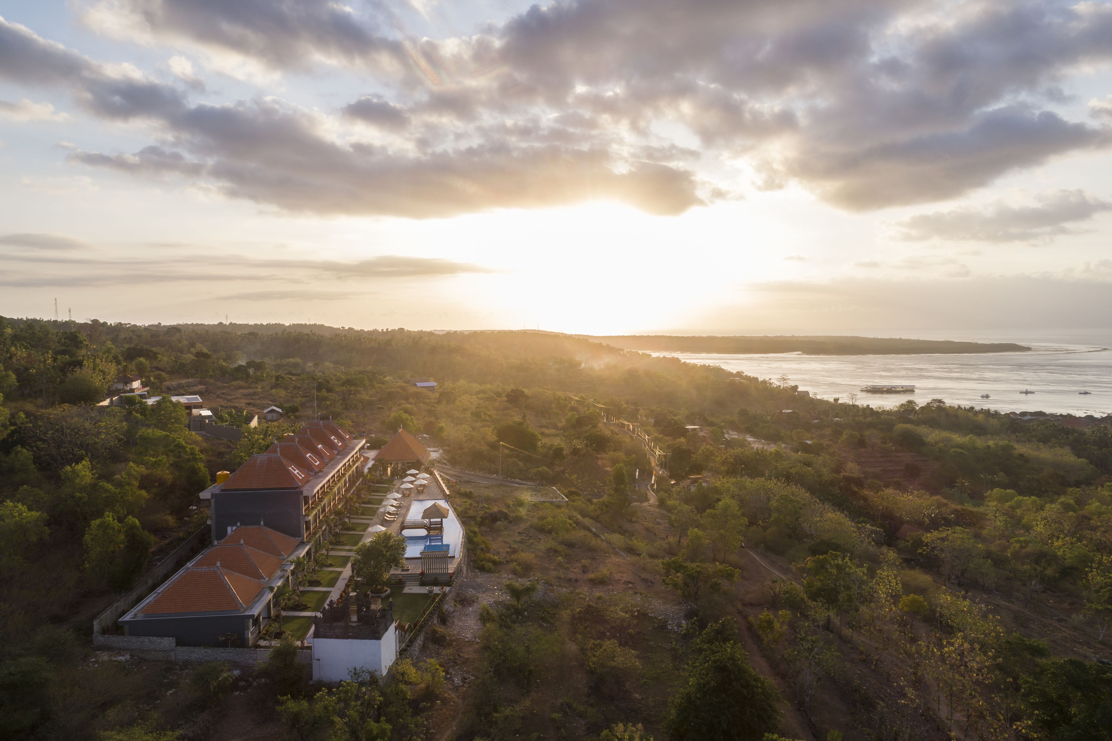 An aerial view of a resort with multiple buildings, a beach, and a sunset.