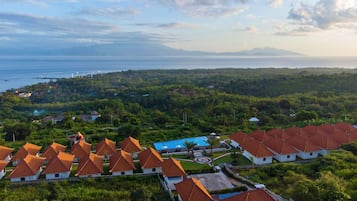 Ein Resort mit mehreren Gebäuden, roten Ziegeldächern, einem Schwimmbad und Blick auf das Meer und die Berge.
