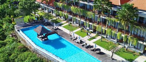 A resort with a large swimming pool, multiple guest rooms, and lush greenery.