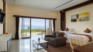 A hotel room with a large sliding glass door leading to a balcony, a sofa, a bed, and a television on the wall.