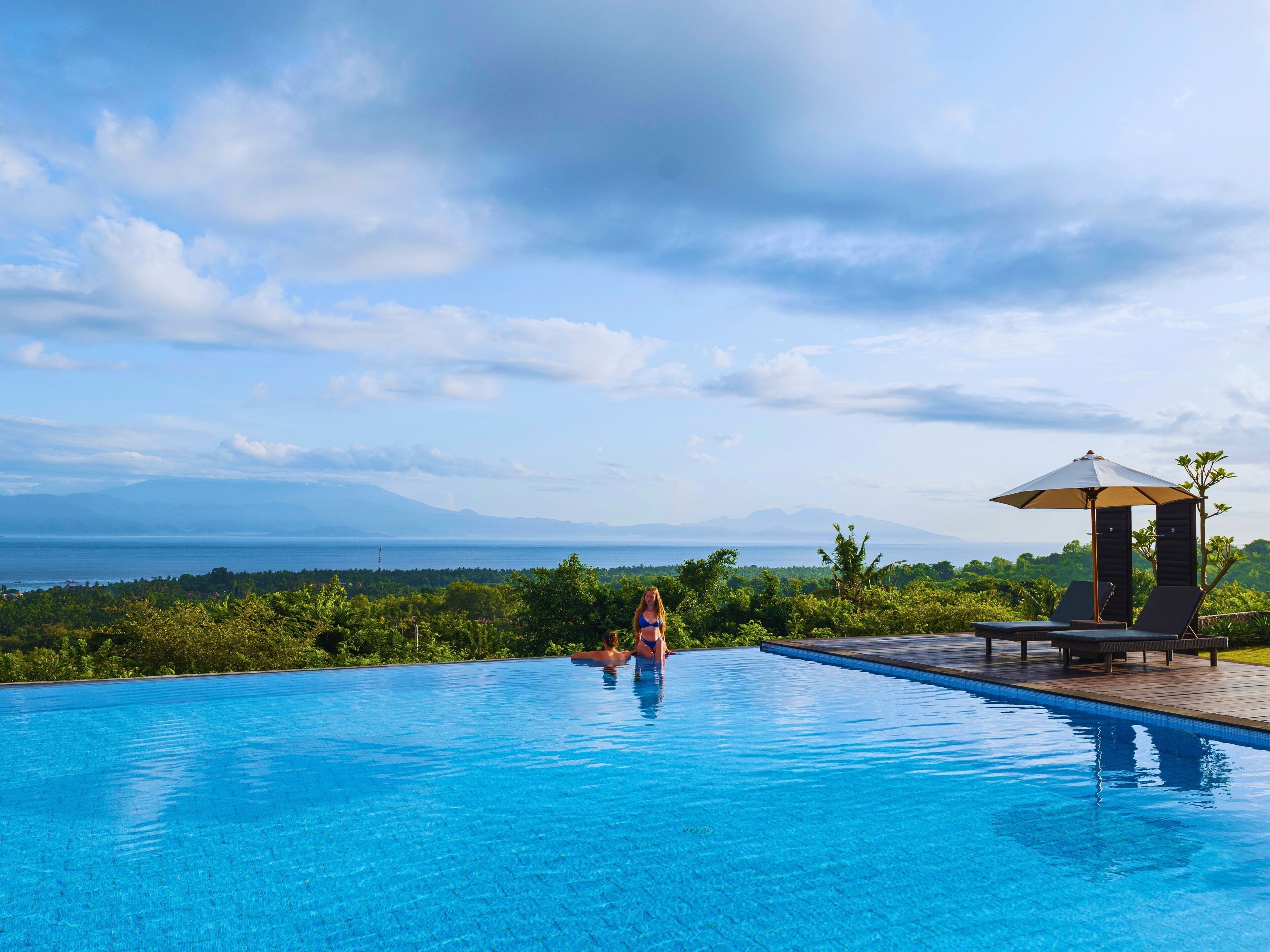A swimming pool with a view of mountains and the sea.