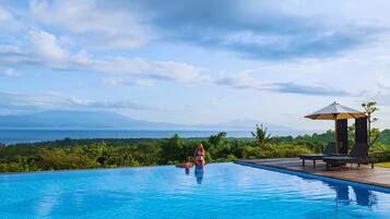 A swimming pool with a view of mountains and the sea.