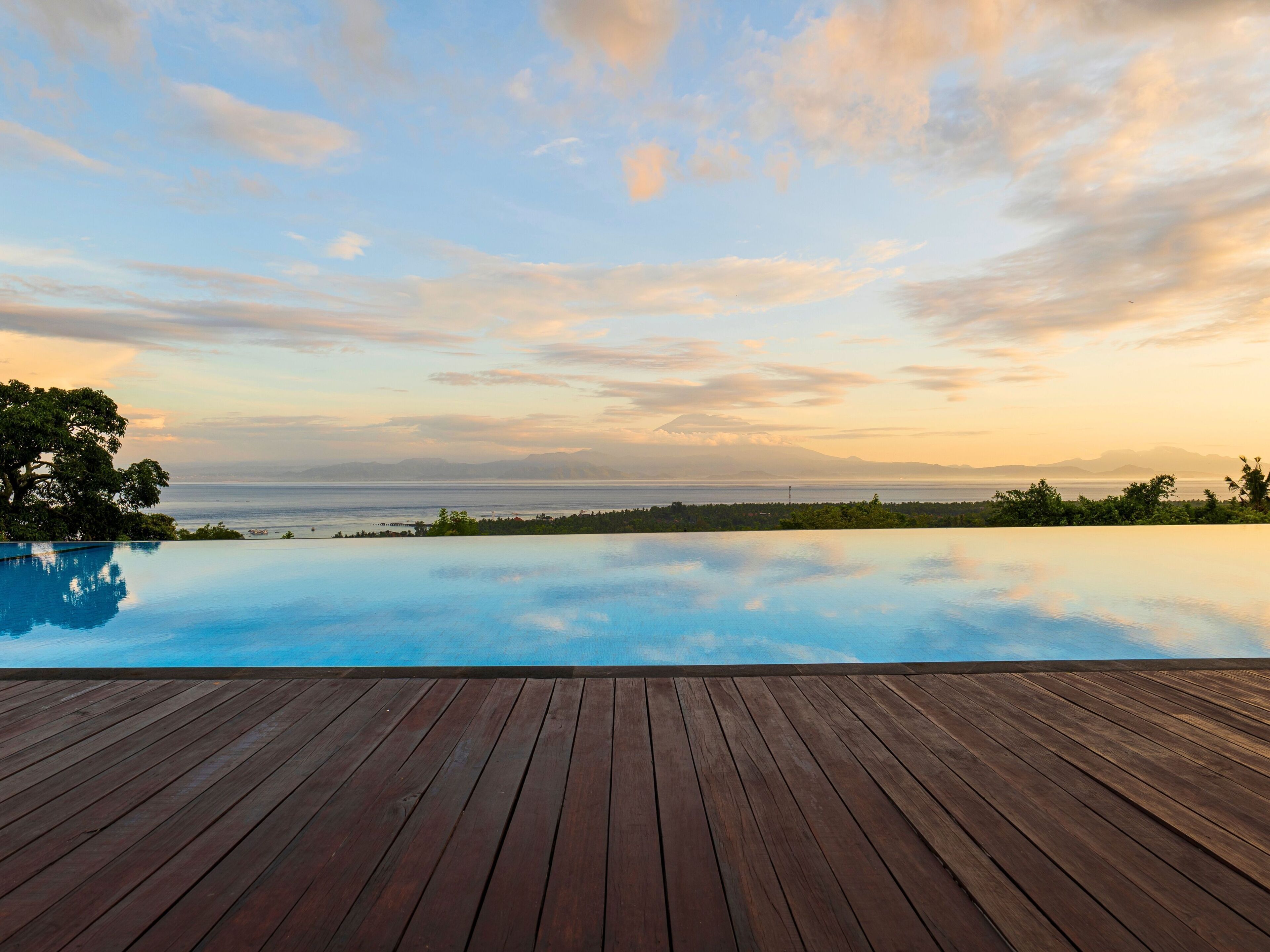 A wooden deck with a clear view of the ocean and distant mountains.