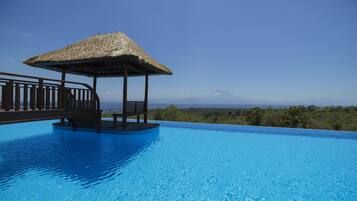 Relax by the serene pool surrounded by a lush landscape and distant mountains.
