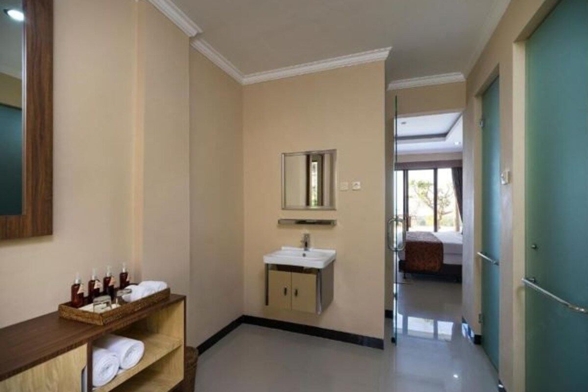 Un baño de hotel con tocador de madera, lavamanos y espejo.
