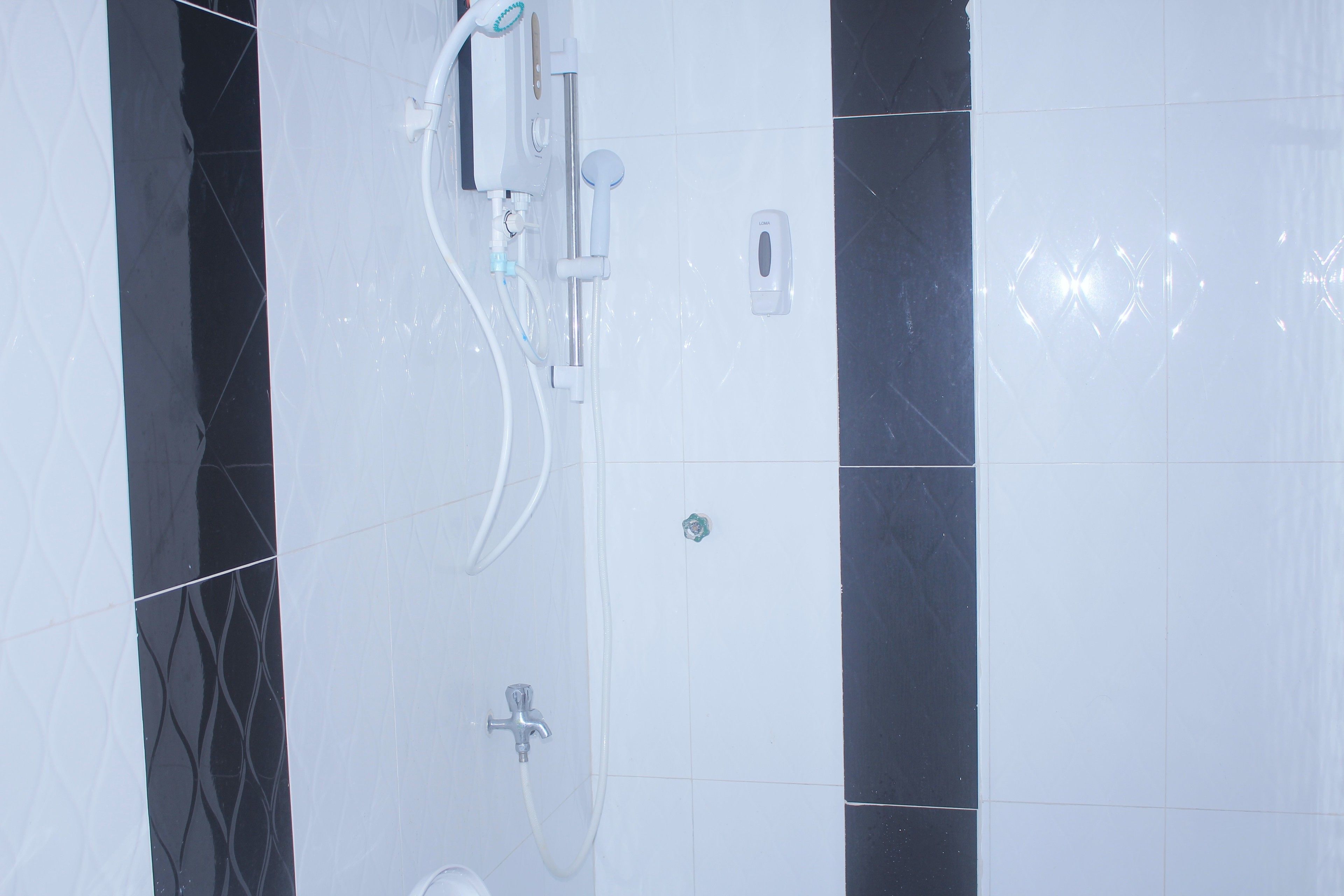 Un baño con ducha, secamanos y dispensador de jabón en la pared.