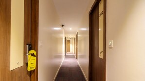 Un pasillo de hotel con puertas de madera, piso alfombrado y un cartel que indica un cuarto para bebés.