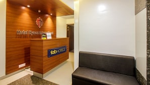 Un mostrador de recepción de hotel con detalles de madera y un logotipo en la parte superior. Hay un letrero azul con el texto 