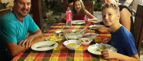 A family dining at an outdoor table with a checkered tablecloth.