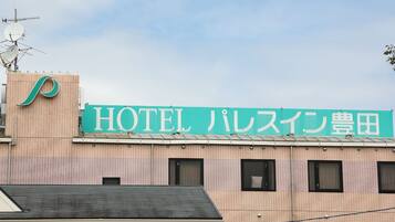 A hotel sign with Japanese characters, a tiled facade, and a satellite dish.
