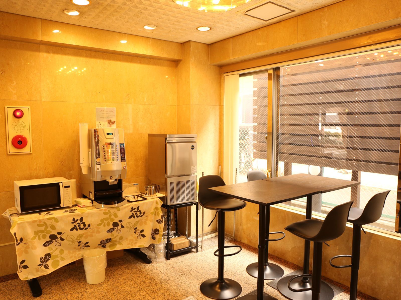 A small room with a table, chairs, a coffee machine, a microwave, and a refrigerator.