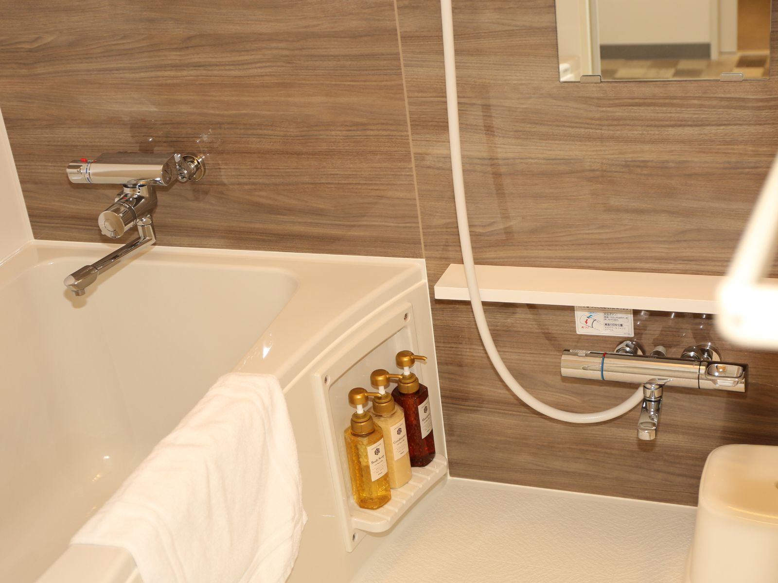 Un baño con bañera, ducha y repisa con artículos de aseo.