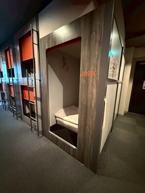 A room with bunk beds, a small desk, and a bulletin board.