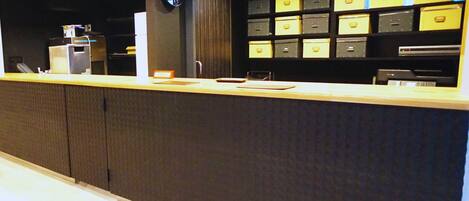 A reception area with a counter, a clock, and storage boxes.