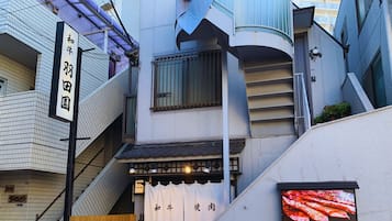 A narrow alley with a restaurant entrance, wooden benches, bicycles, and a signboard.