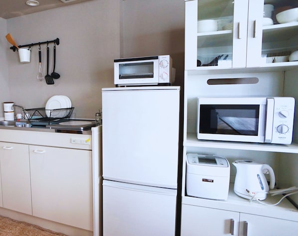 A compact kitchen with a microwave, toaster, and refrigerator. - Beagle Tokyo Hostel and Apartments (Tokyo)