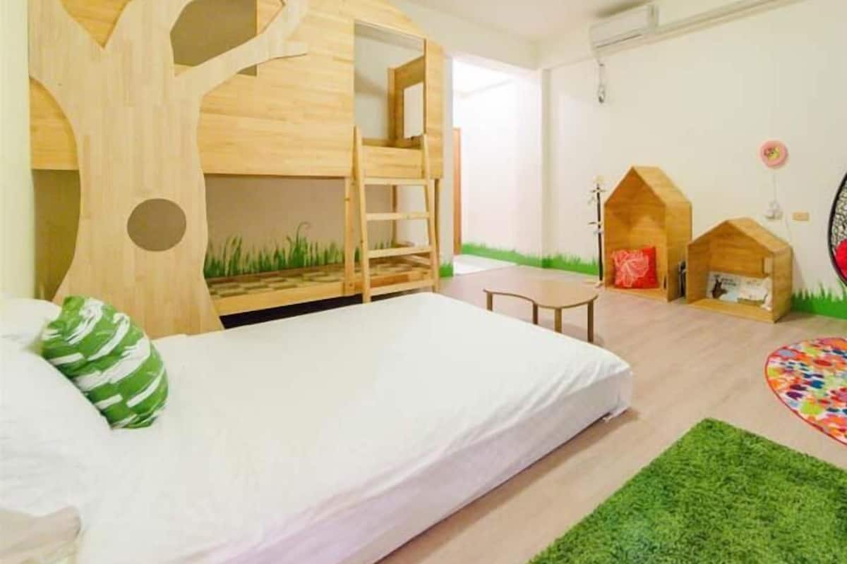A room with a bunk bed, a small table, and two playhouses.