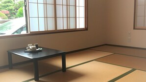 A room with tatami mat flooring, a low table with a tea set, and a shoji screen window. - Guesthouse Hakuka - Hostel (Kanazawa)